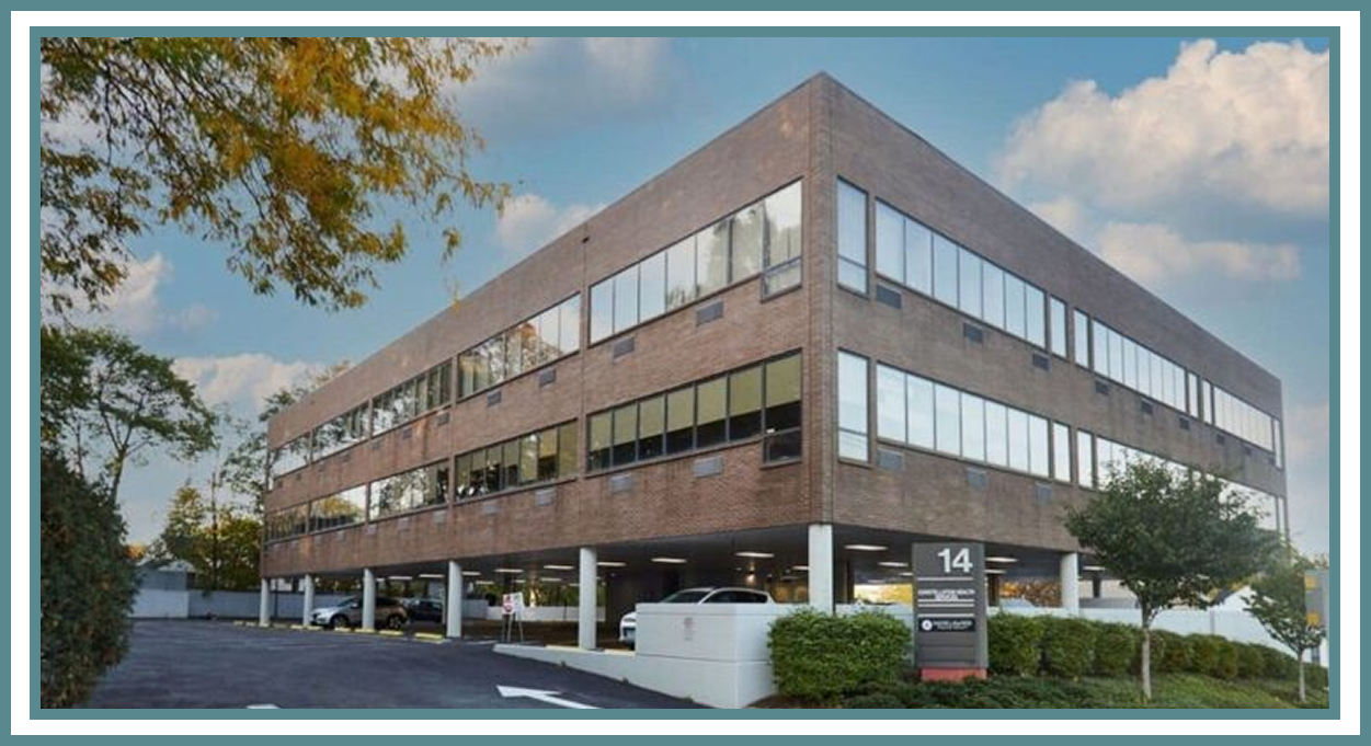 Brick office building with parking and trees.