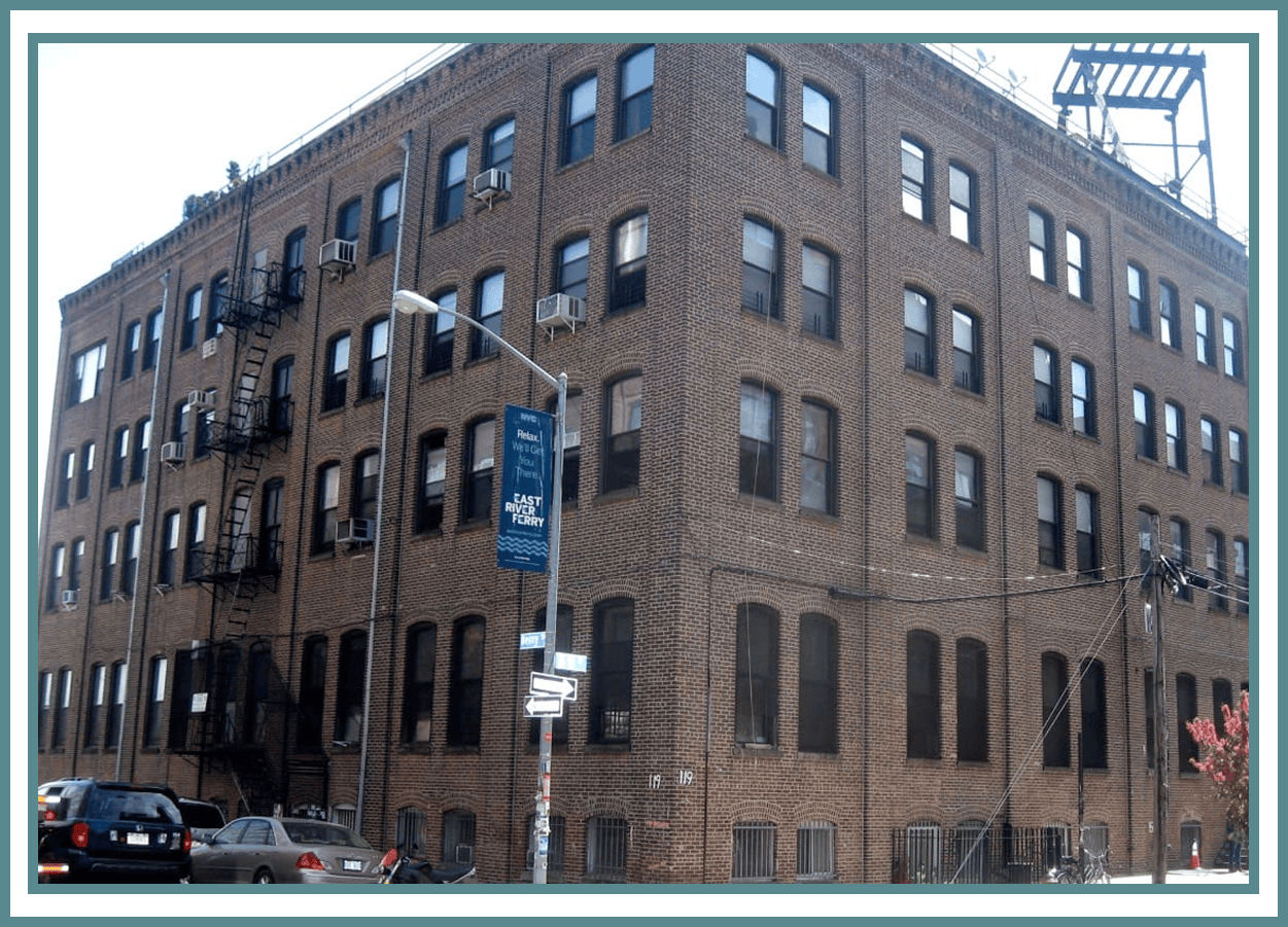 Brick building with fire escapes and cars.